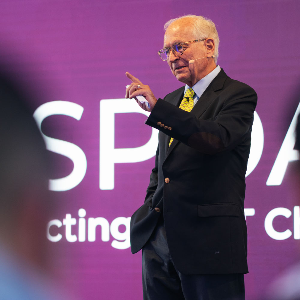 Keynote-Speaker auf der Bühne des MSP Day vor violetter Event-Leinwand